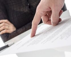 Male hand showing a woman where to sign a paper.