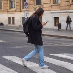 Pedone che attraversa la strada con telefono