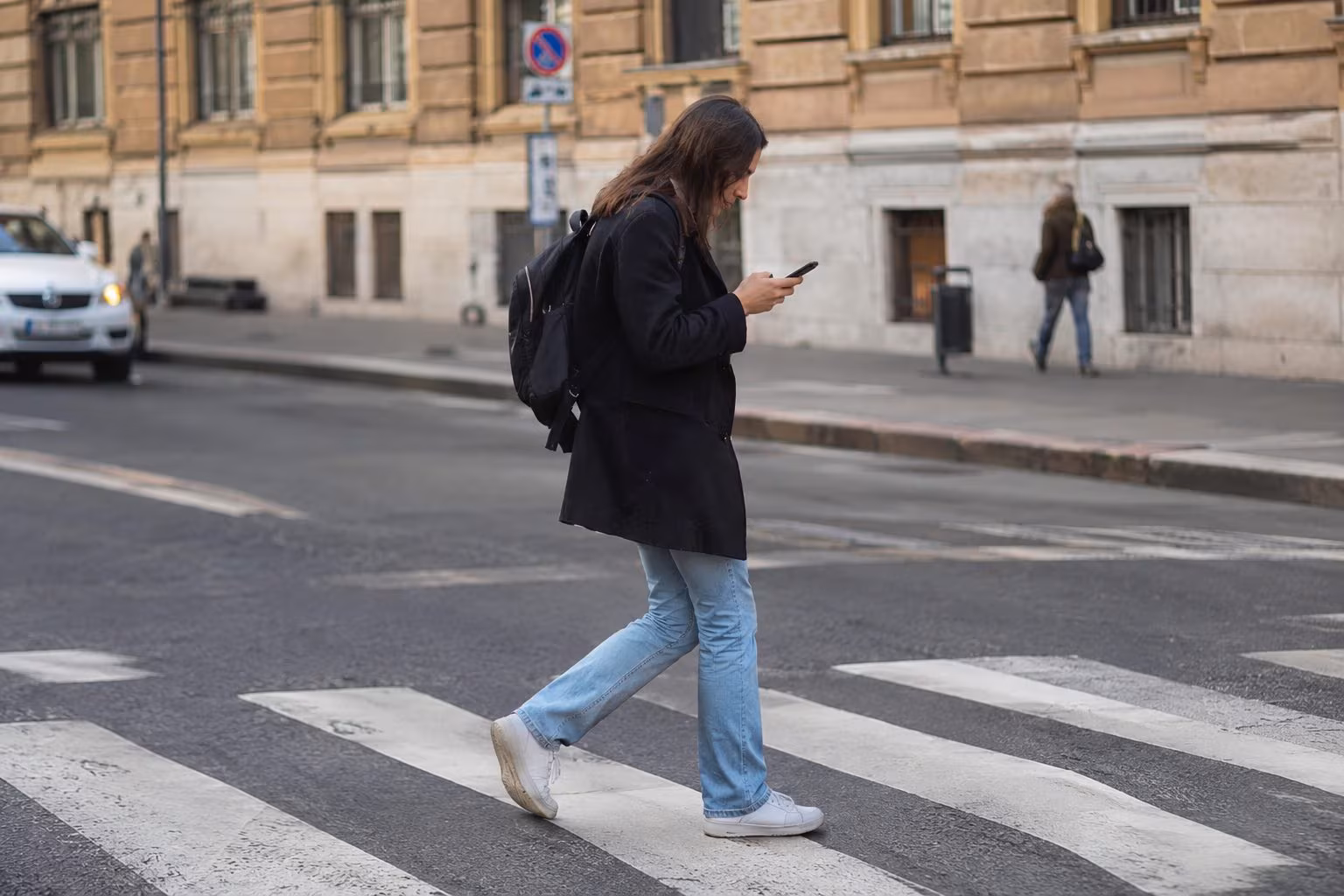 Pedone che attraversa la strada con telefono